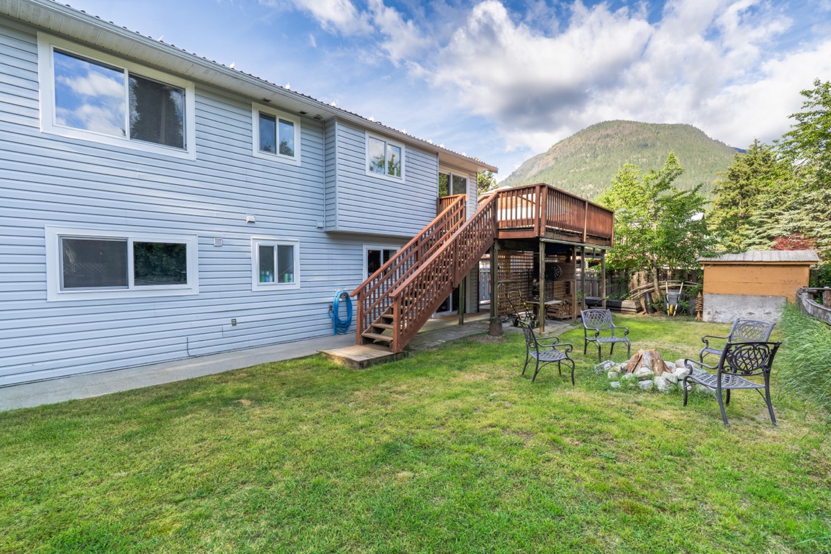 Backyard with lawn, fire pit seating and a mountain beyond the house