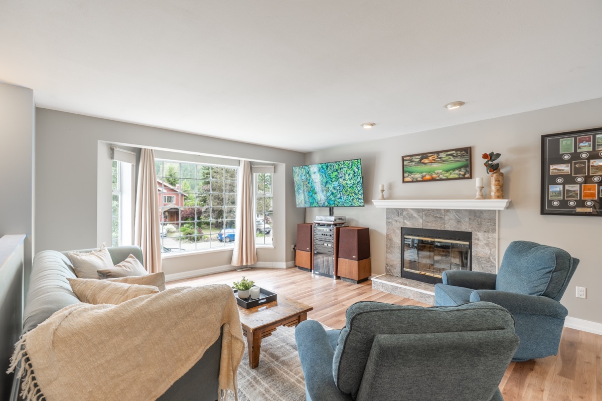Living room with a fireplace, TV and large front window