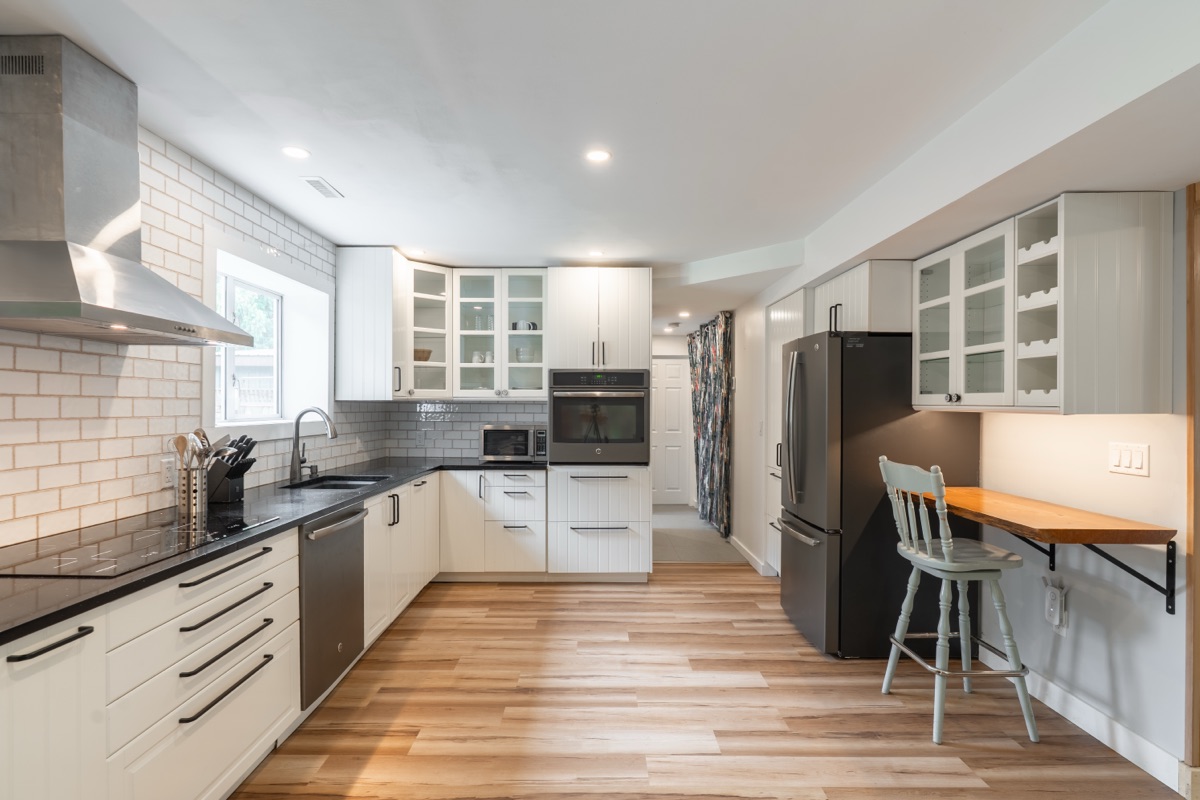 White kitchen with tile backsplash and a wood bar shelf