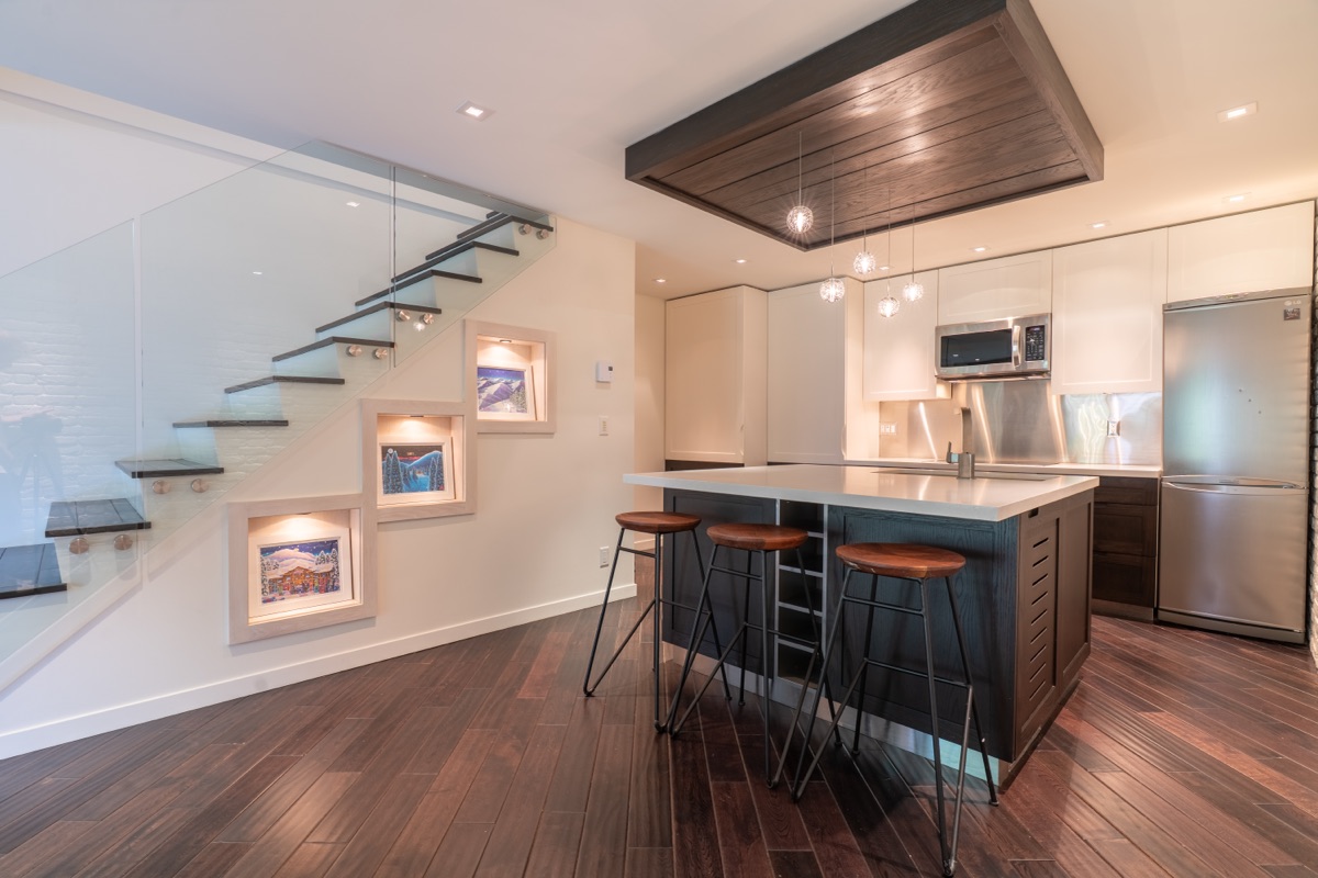 Kitchen with island, bar stools and a glass staircase