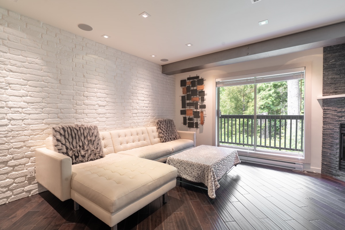Living room with a white brick wall and cream sectional sofa