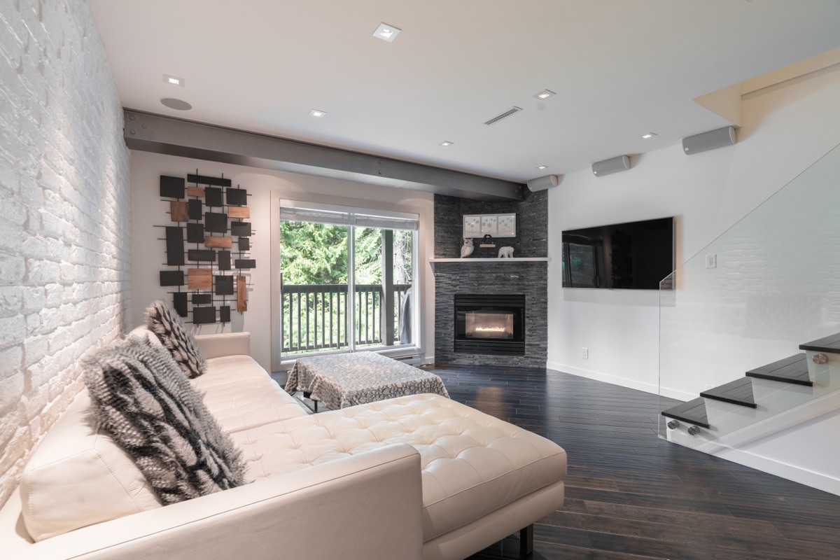Living room with a fireplace, wall-mounted TV and glass stair railing
