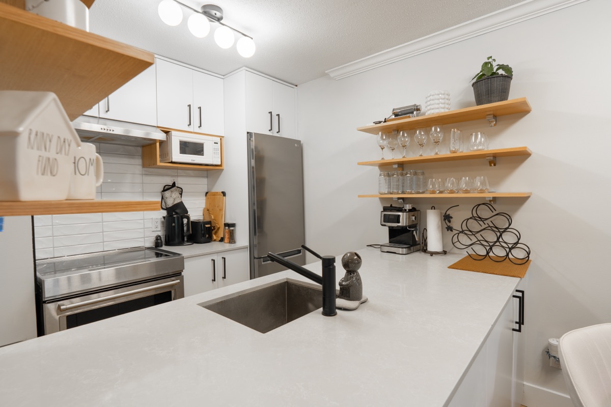 Kitchen counter with open wood shelving and a sink